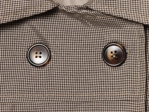Gros plan sur la texture pied-de-poule et les boutons marbrés de la chemise d'été