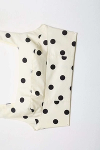 Detail of cream fabric featuring classic large black polka dots and fine woven texture