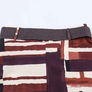 Detail of retro geometric print fabric with a brown braided waist belt on the skirt