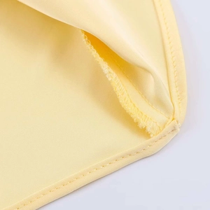 Detail shot of high-quality flat seam stitching on smooth yellow satin fabric