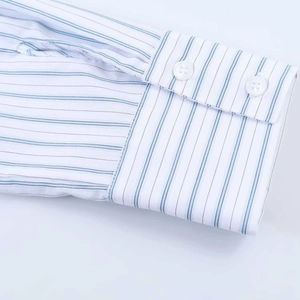 Détail des poignets d'une robe chemise à rayures blanches et bleues avec deux boutons blancs