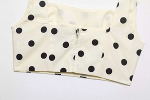 Close-up of cream crop top with black polka dots featuring a back silver zipper detail