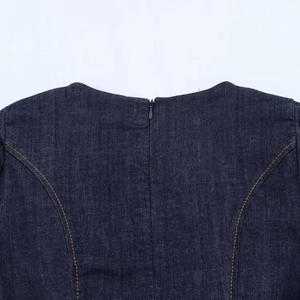 Close-up of invisible back zipper and orange stitching on navy blue denim dress fabric