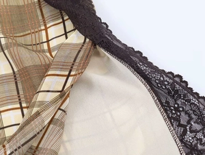 Dettaglio di tessuto scozzese con bordo in pizzo marrone scuro su un top estivo