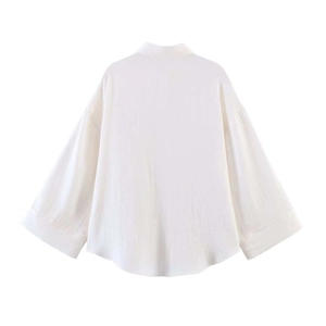 Detailed back view of a white oversized shirt showing textured fabric and curved hemline