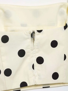 Detailed view of silver metal zipper closure on beige polka dot sleeveless top and skirt set