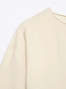Detail of the high-quality stitching on the round neck of this beige ruffled dress