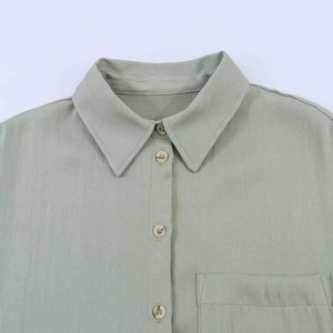 Close-up of light green blouse neckline, buttons and chest pocket details