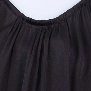 Close-up detail of pleated round neckline on a black silk textured halter backless dress