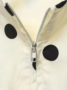 Close-up of a silver zipper detail on a cream polka dot fabric with smooth texture