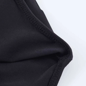 Dettaglio ravvicinato della cucitura overlock sul body nero con decoro metallico