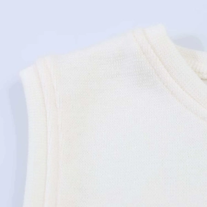 Détail de débardeur en maille crème montrant l'encolure ronde et la couture d'épaule