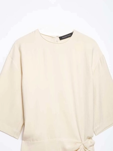 Detail of apricot dress featuring side knot drapery and high-quality twill fabric texture