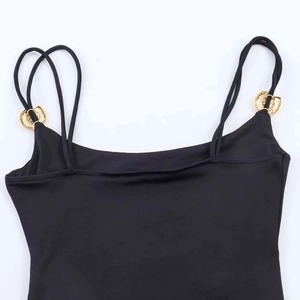 Dettaglio del body in maglia nera con doppie spalline e fibbie in metallo dorato sbalzato
