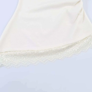 Détail d'un top sans manches crème avec ourlet en dentelle festonnée et texture tricot