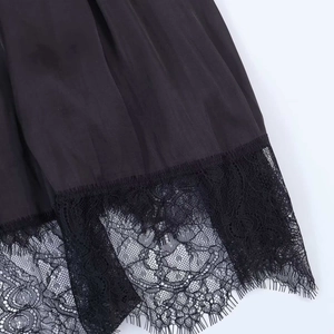 Detail of silky black satin fabric with intricate floral eyelash lace trim on the hemline