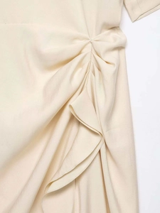 Detailed view of the apricot pleated fabric and ruffled hem on the stylish summer dress