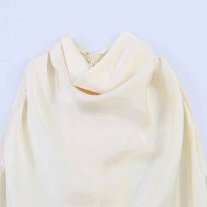Detail of elegant cream satin dress showing cowl neck design and smooth glossy fabric