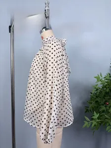 Detail des Stehkragens mit eleganter Schleife an einer gepunkteten Chiffon-Bluse