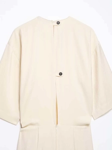 Close-up of the elegant open back detail with black buttons on a cream-colored dress