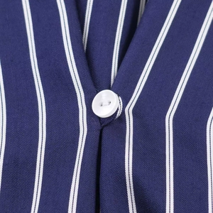 Detail of white resin button and vertical navy stripes on a woven shirt fabric