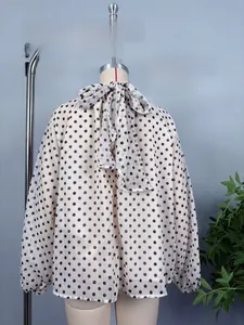 Detail der cremeweißen Langarm-Tupfenbluse aus Chiffon mit Schleife am Rücken