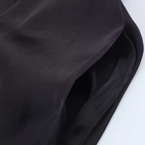 Macro shot of high-density black satin fabric detail with precision stitching and pocket
