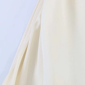 Macro detail of the fine twill texture and stitching on a beige silk texture dress