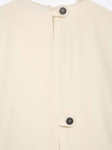 Detail view of apricot dress back closure with two brown buttons and woven texture