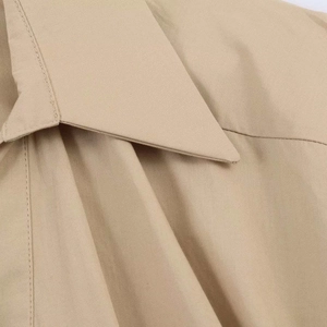 Gros plan sur la texture en sergé beige et les coutures du col à revers de la robe