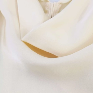 Detailed view of the smooth cream satin fabric and soft draped neckline texture