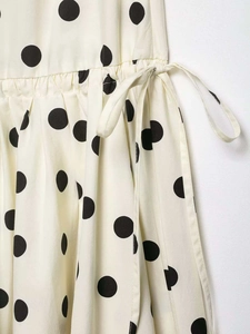 Close-up of cream polka dot fabric with waist drawstring and pleated texture detail