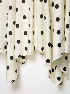 Detail of polka dot skirt featuring an asymmetric hem and lightweight cream fabric
