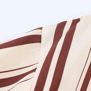 Close-up of striped woven fabric detail on midi dress with precise sewing and texture