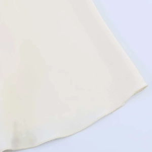Detailed macro view of the cream silk texture hemline with high-quality stitching detail