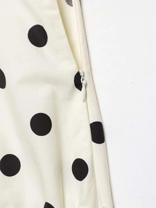Detailed macro view of the invisible zipper and black polka dot pattern on beige fabric