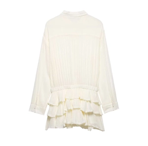 Detail view of the back tiered ruffle hem and pleats on a cream long-sleeved shirt dress