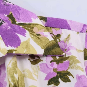 Detail of floral shirt collar featuring large purple flowers and green leaves on white