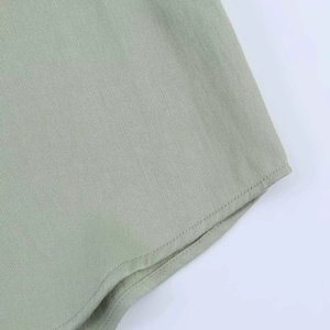 Detail of light green twill fabric shirt with curved hemline and precision stitching