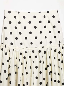 Close-up of a white polka dot midi skirt featuring waist pleats and fabric texture