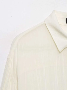 Detail of off-white shirt featuring a lapel collar and vertical textured crepe fabric