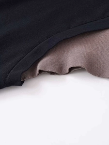Close-up of color-block knit top showing black and purple ribbed fabric layering details