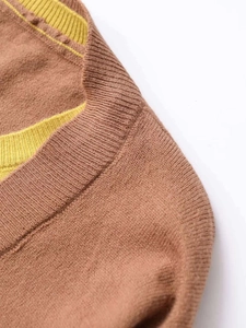 Detail of round neckline and shoulder on brown knit top with yellow ribbed trim