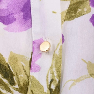 Detailed close-up of floral print fabric and a golden metal button on the waist belt