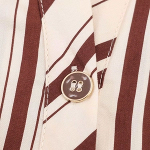 Detail of elegant brown striped dress showing a premium marble button with gold rim