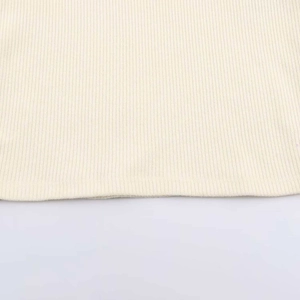 Macro shot of beige ribbed knit fabric showing vertical texture and soft elastic fibers