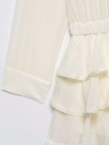 Detail of beige layered tulle dress featuring delicate white lace trim and ruffle accents