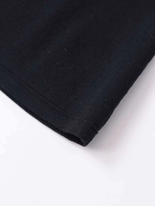 Macro detail of the fine-knit black fabric texture and premium hem finish on the sweater