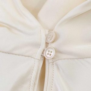 Detailed macro view of the double button closure and the smooth silk-textured woven fabric