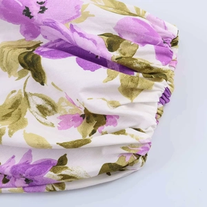Close-up of elastic shirring detail on white summer dress with purple floral patterns